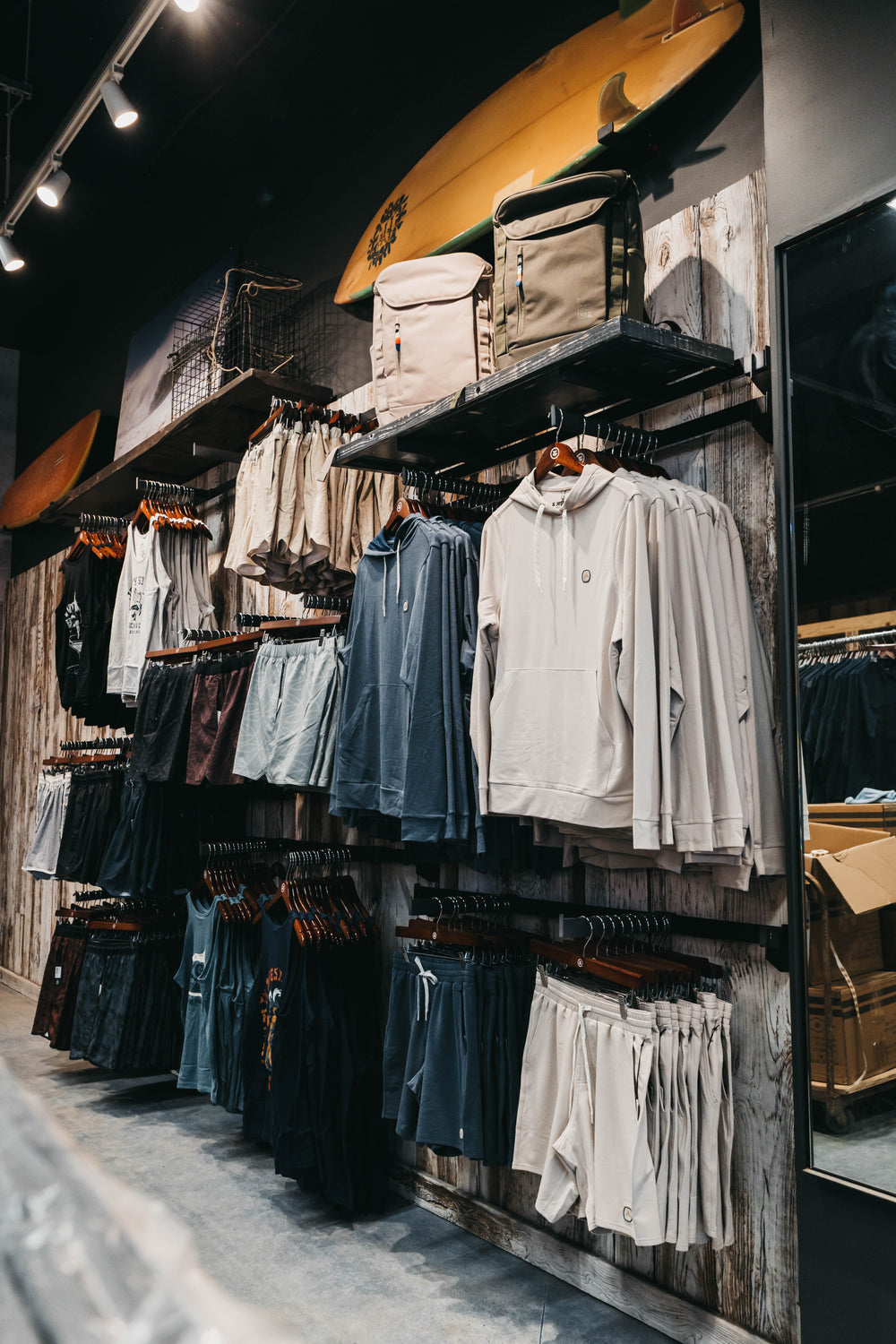 Clothing store interior with hanging clothes on wooden racks.